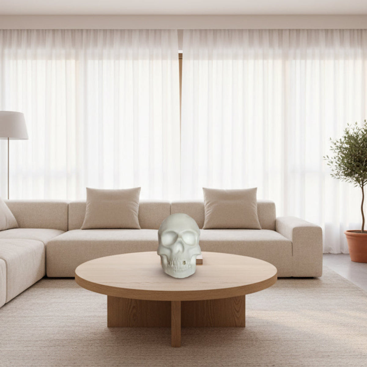  Large Skull Sculptures - white ceramic skull displayed on a minimalist wooden table in a bright, modern room with large windows and light wood floors.