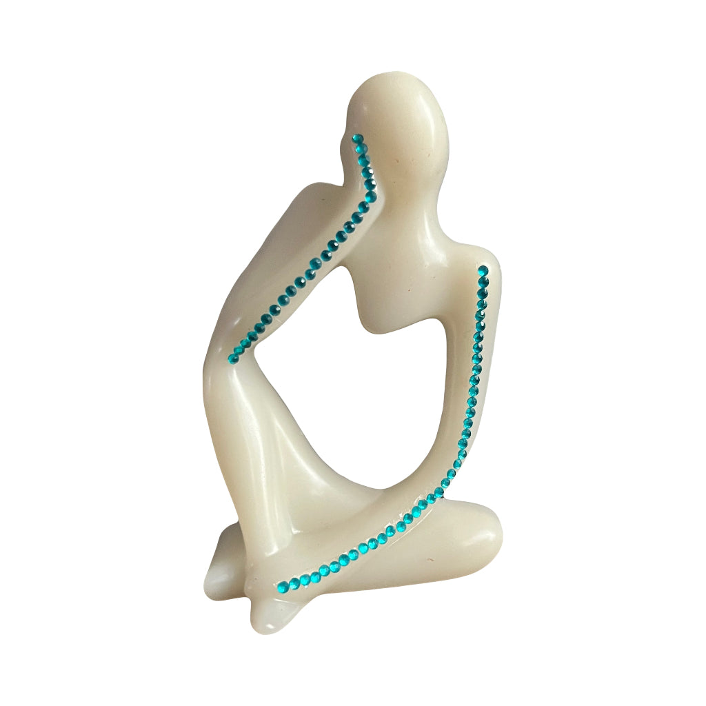 Nordic Resin Thinker - A minimalist figurative sculpture of a seated human figure in a cream-colored stone or resin, accented with small turquoise blue rhinestones along the spine, arms, and legs, set against a plain white background.