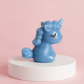 Unicorn Statue Figurines - A light blue unicorn figurine sitting on a white cylindrical pedestal against a solid pink background.