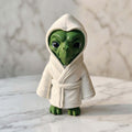 ET Alien Figurine - A green alien figurine wearing a white hooded robe, standing on a white marble surface with a matching marble background.