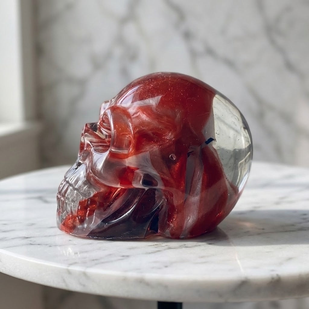 Gothic Skulls - Side view of a clear skull-shaped object with red, white and blue flag embedded with roses and petals on a white surface