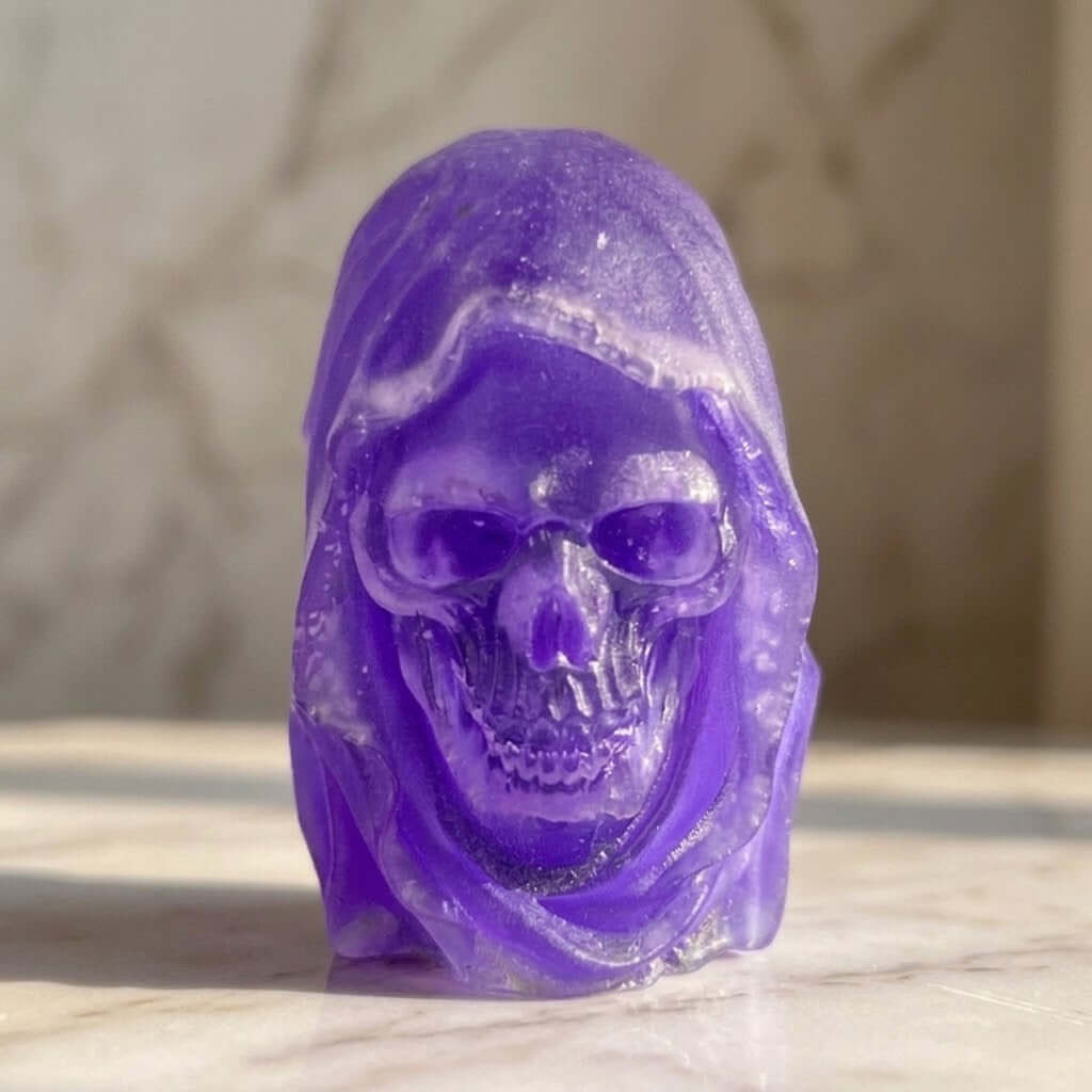 Hooded Skull Figurines - A translucent purple resin skull figurine with a hooded, ghostly appearance, standing on a light marble surface with a blurred marble background.