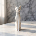 3D Printed Cat Figurine - A white cat figurine sitting upright on a light marble surface, wearing a rhinestone-studded collar, with a softly blurred grey marble background.