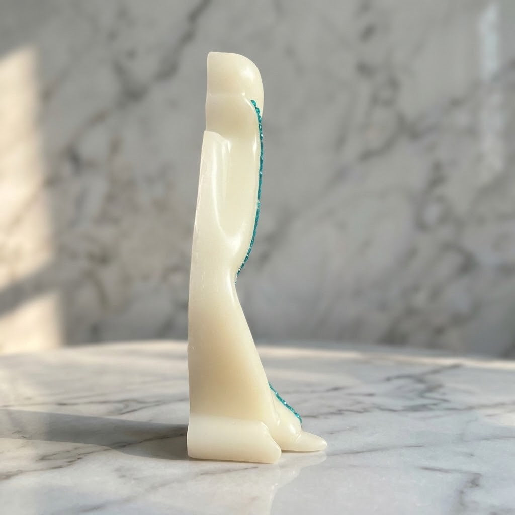 Nordic Resin Thinker - Side view of a small sculptural figurine of a standing figure in ivory, photographed on a white marble surface with a softly blurred marble background.