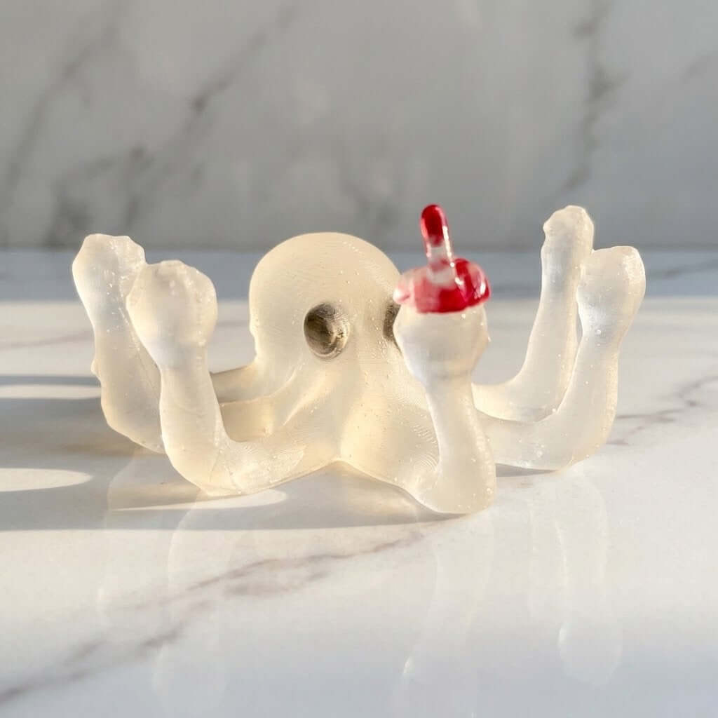 Novelty Octopus Figurine - A translucent off-white resin octopus-shaped holder with a small red finger pointing upwards, resting on a white marble surface.
