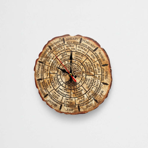 Celtic Calendar Clock A circular wall clock designed to look like a natural tree log slice, featuring astrological and zodiac symbols and text. The clock has black hands with red tips and is shown against a plain light gray background.