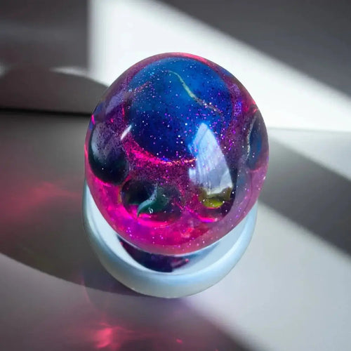 Colour changing egg filled with marbles on a reflective surface with light reflections
